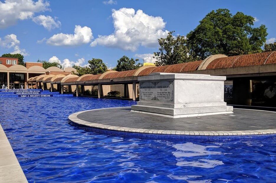 A serene memorial pool with a central stone monument surrounded by a blue-tiled water feature and arched walkways in Atlanta, Georgia.