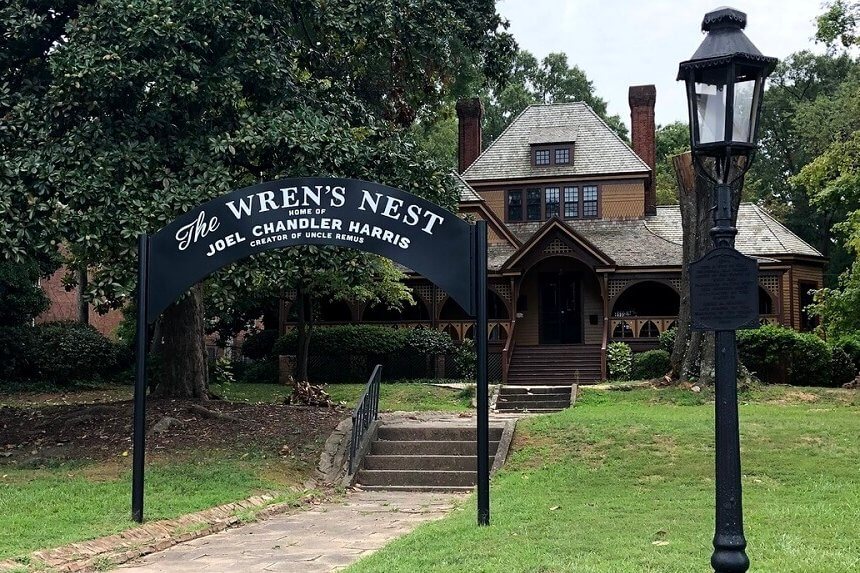 A quaint Victorian-style house with a distinctive gable roof and a welcoming sign reading 'The Wren's Nest, Home of Joel Chandler Harris' in Atlanta, Georgia.