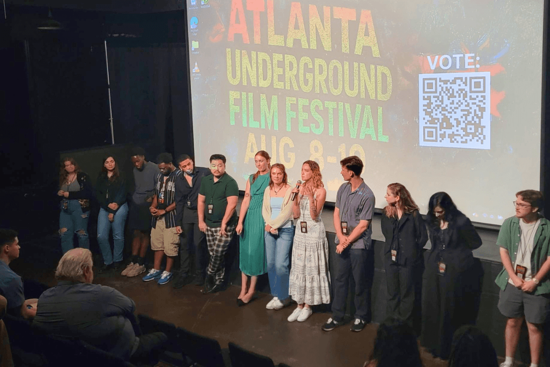 A diverse group of young people stand on stage at the Atlanta Underground Film Festival, ready to present or accept an award in Atlanta, Georgia.