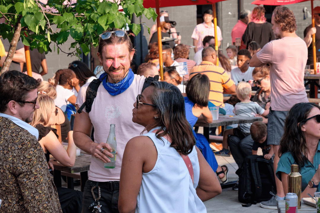 A lively outdoor marketplace with people enjoying food, drinks, and entertainment under colorful umbrellas in Atlanta, Georgia.