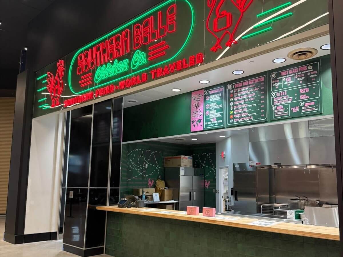 A vibrant restaurant with a neon sign featuring a rooster and the words 'Southern Belle Chicken Co.' in Atlanta, Georgia.