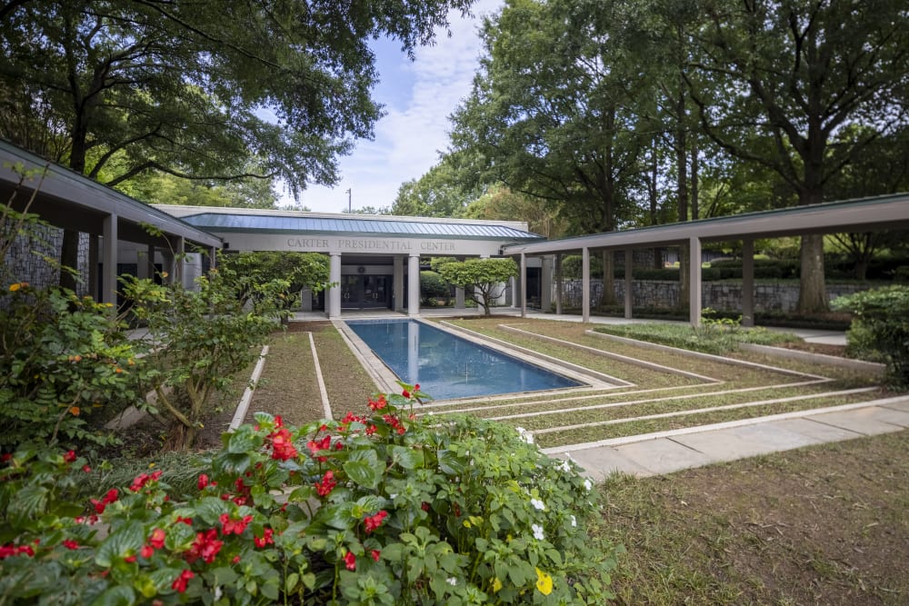 A serene courtyard with a rectangular pool, surrounded by lush greenery and colorful flowers in Atlanta, Georgia.