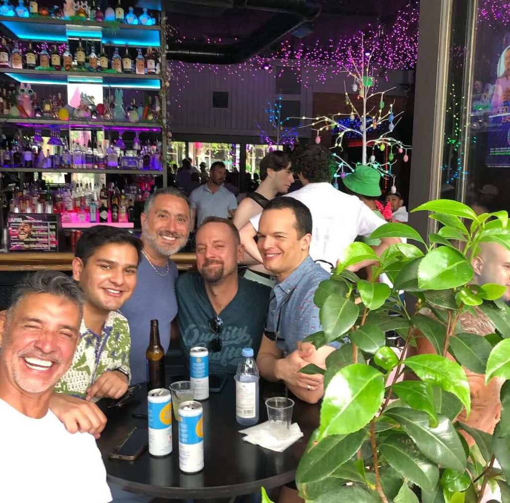 Atlanta Pride Survival Guide 3 Five men smiling and laughing together at a bar table with drinks in Atlanta, Georgia.