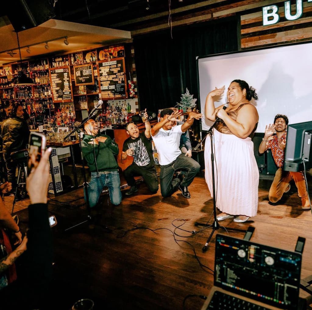 A lively karaoke performance in a dimly lit bar with enthusiastic participants and a diverse crowd in Atlanta, Georgia.