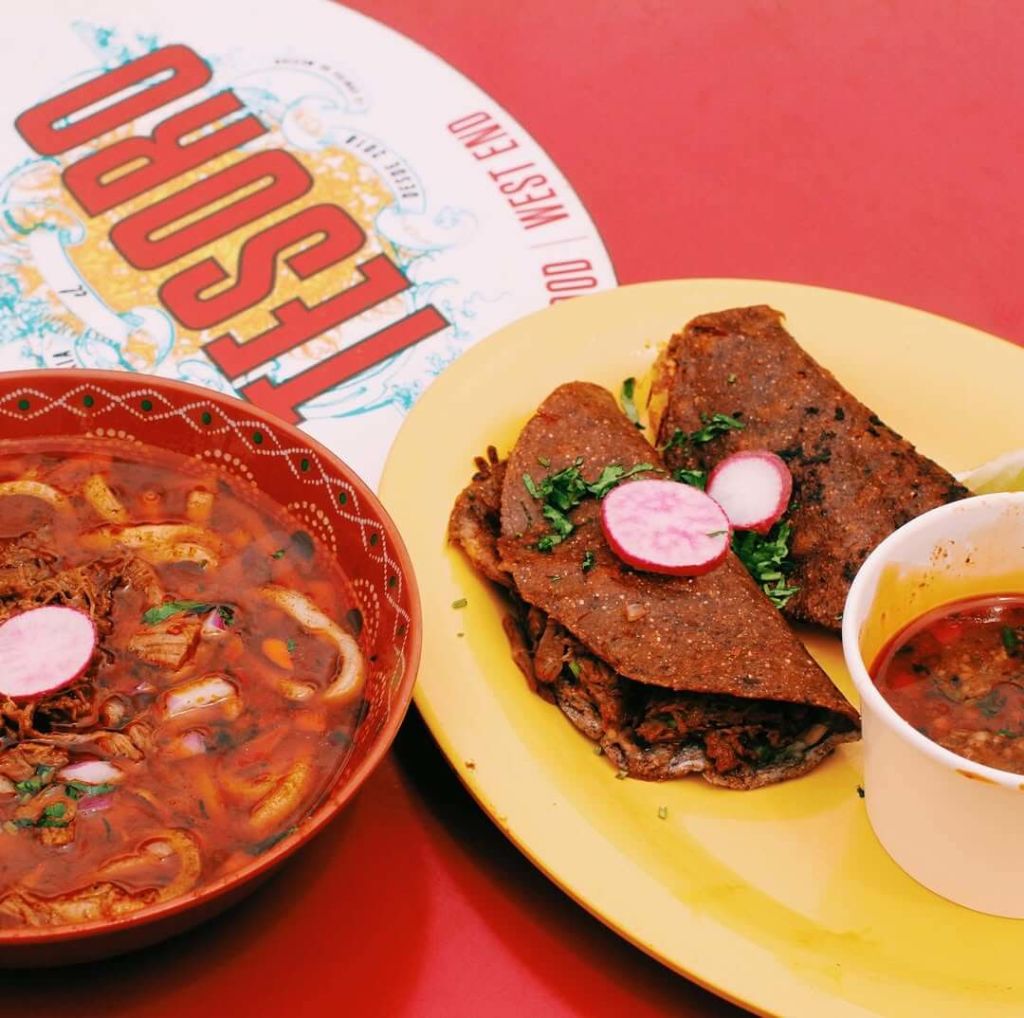 A vibrant meal featuring red soup with radishes and tacos with radish slices on a yellow plate in Atlanta, Georgia.