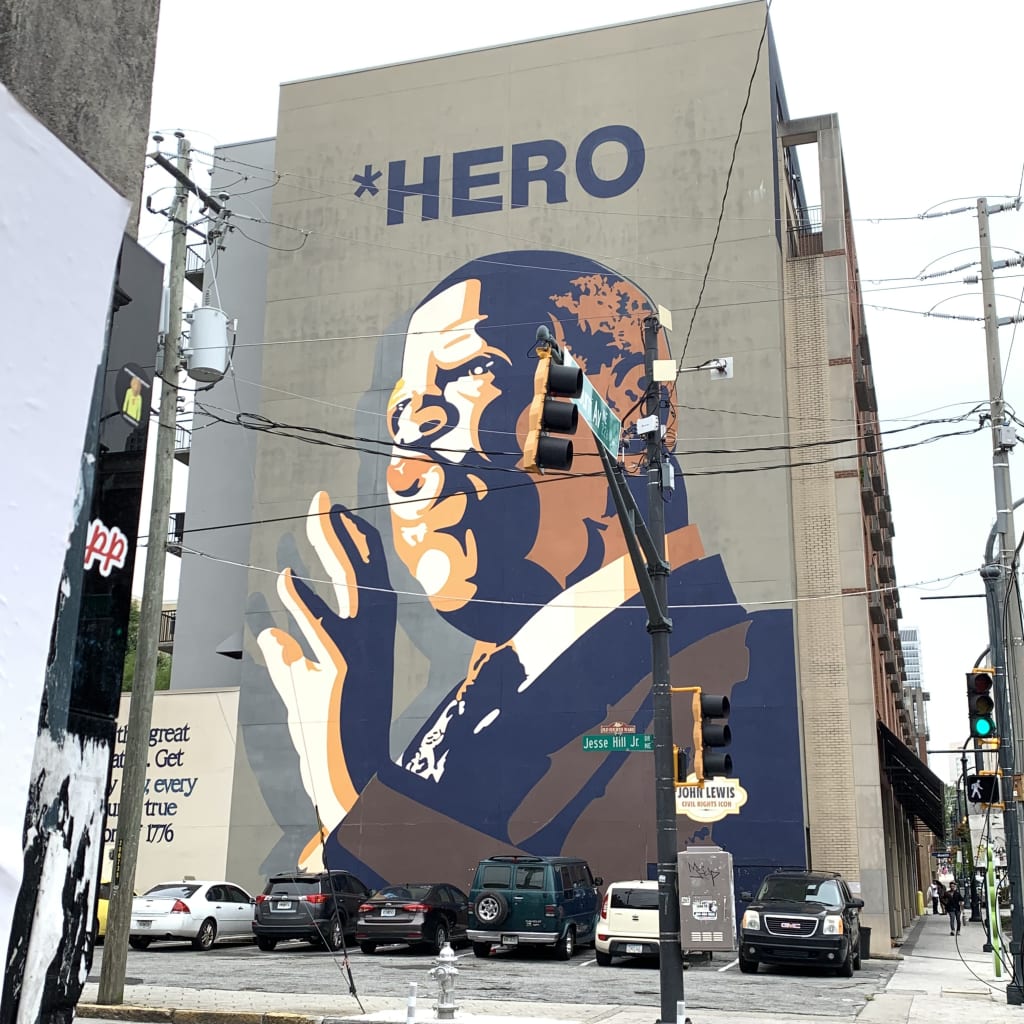 Large mural of John Lewis with raised fist on building wall in Atlanta, Georgia.