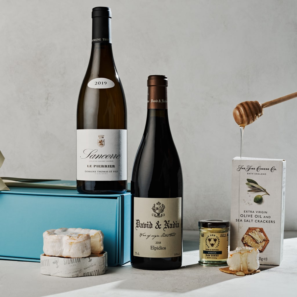 Wine bottles, cheese, crackers, and honey on a table with a blue box in Atlanta, Georgia.
