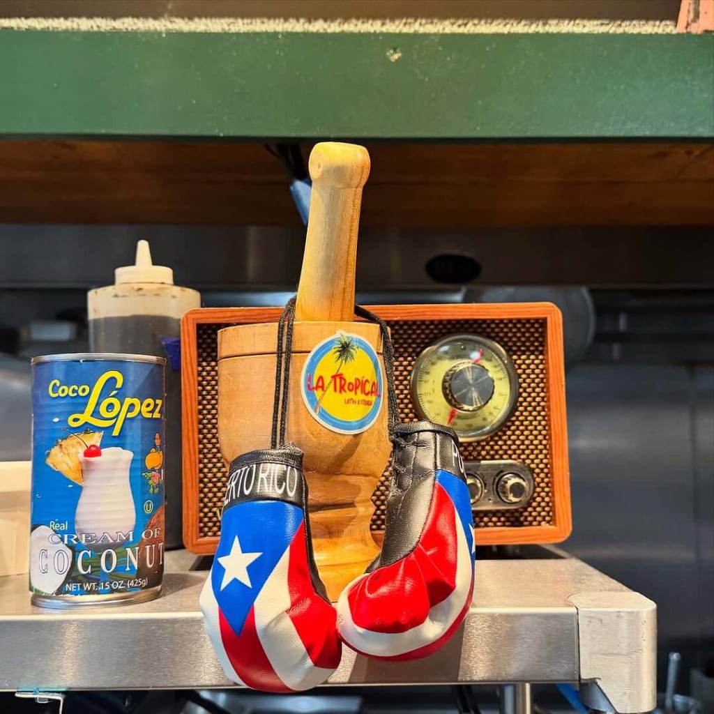 A wooden mortar and pestle with a radio and coconut cream can on a metal shelf in Atlanta, Georgia.