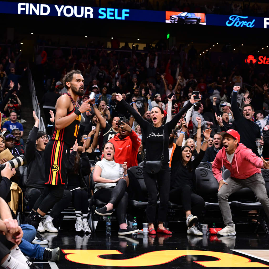 A basketball player celebrates with fans in a packed arena, arms raised in triumph in Atlanta, Georgia.