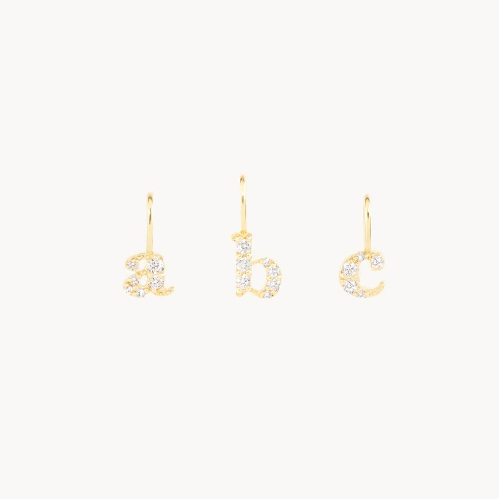 Three delicate gold letter charms, A, B, and C, each adorned with sparkling diamonds in Atlanta, Georgia.