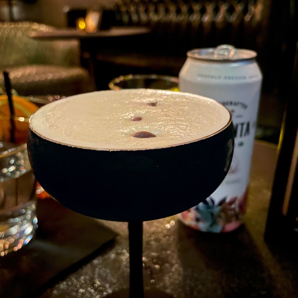 Hidden Bars and Speakeasies in Atlanta You Should Know 2 A dark cocktail glass filled with a creamy white drink sits on a bar table in Atlanta, Georgia.