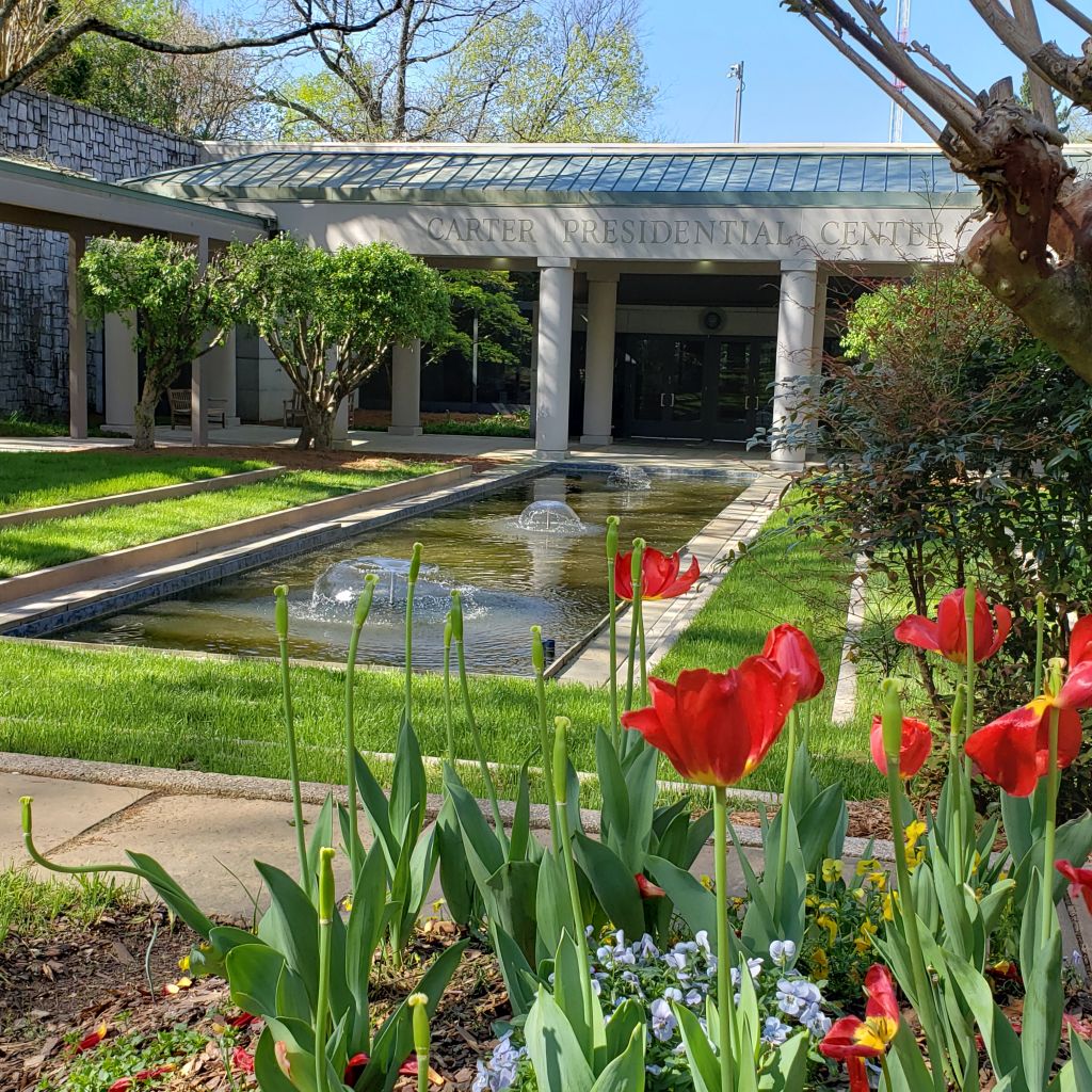 A vibrant garden with red tulips and a water fountain in front of a building with columns in Atlanta, Georgia.