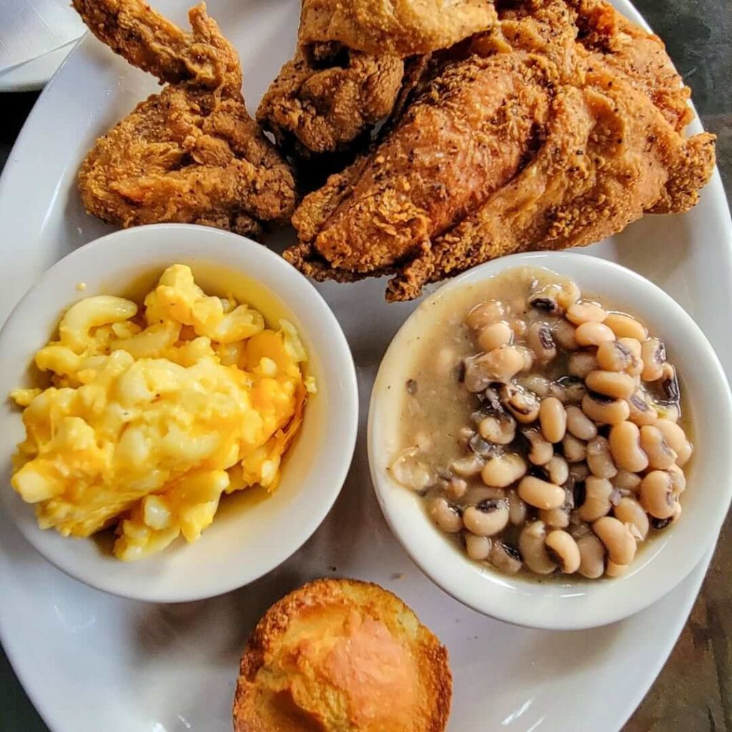 A plate of Southern comfort food featuring crispy fried chicken, creamy macaroni and cheese, savory black-eyed peas, and a fluffy cornbread muffin in Atlanta, Georgia.