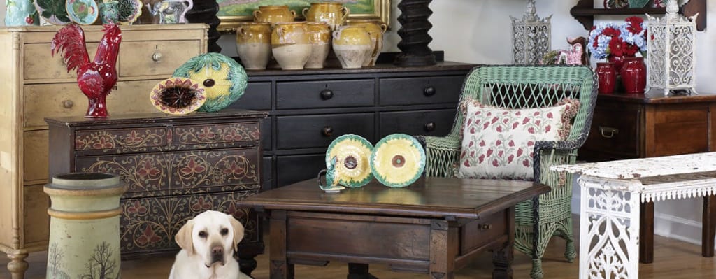 A cozy room with antique furniture, decorative plates, and a friendly dog sitting on the floor in Atlanta, Georgia.