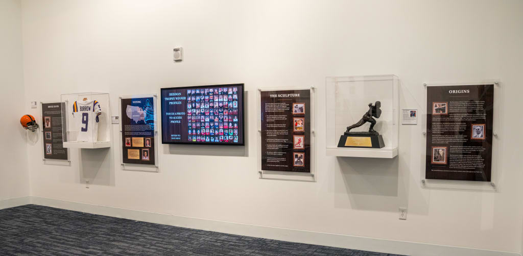 A museum wall display featuring sports memorabilia, including a football helmet, jersey, and trophy in Atlanta, Georgia.