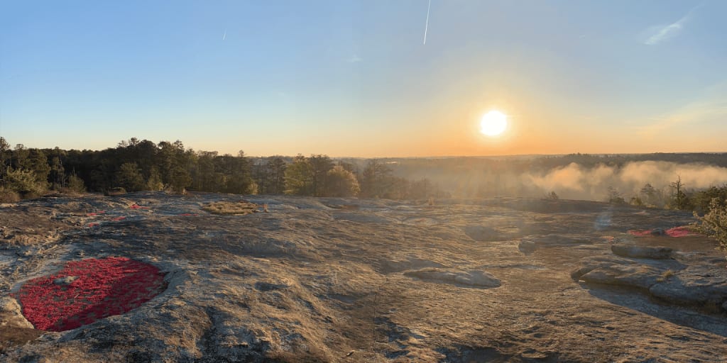 Sunrise over a rocky landscape with a misty valley below and a forest in the distance in Atlanta, Georgia.