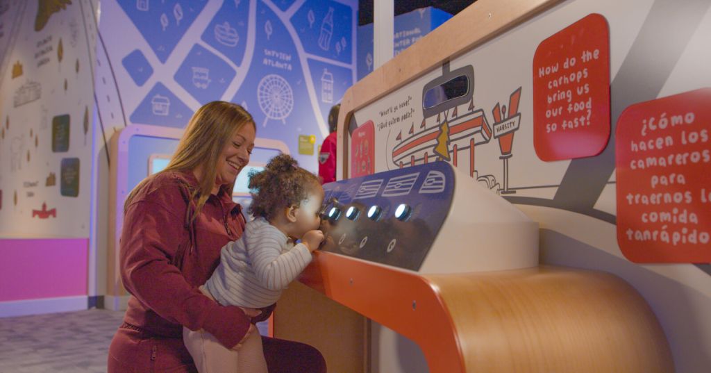 A woman and child interact with a colorful, educational exhibit at a children's museum in Atlanta, Georgia.