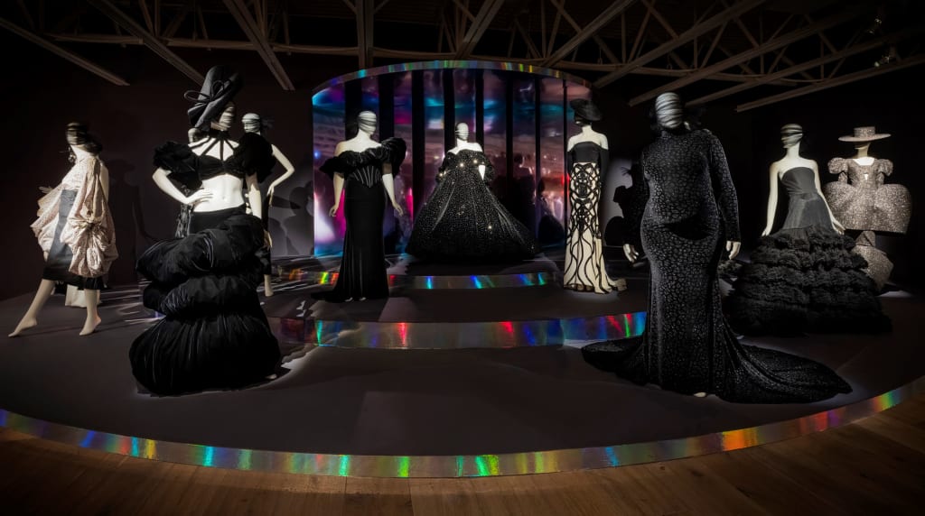 Mannequins in elaborate black dresses with face masks on a circular stage in Atlanta, Georgia.