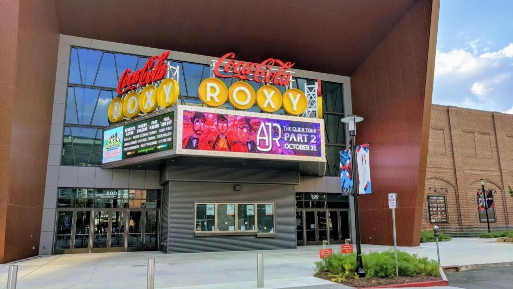 A modern movie theater with a large neon sign featuring the Coca-Cola logo and the name Roxy in Atlanta, Georgia.
