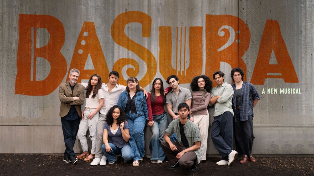 A diverse group of young adults pose together in front of a large, colorful mural spelling out 'BASURA' with the subtitle 'A New Musical' below it in Atlanta, Georgia.