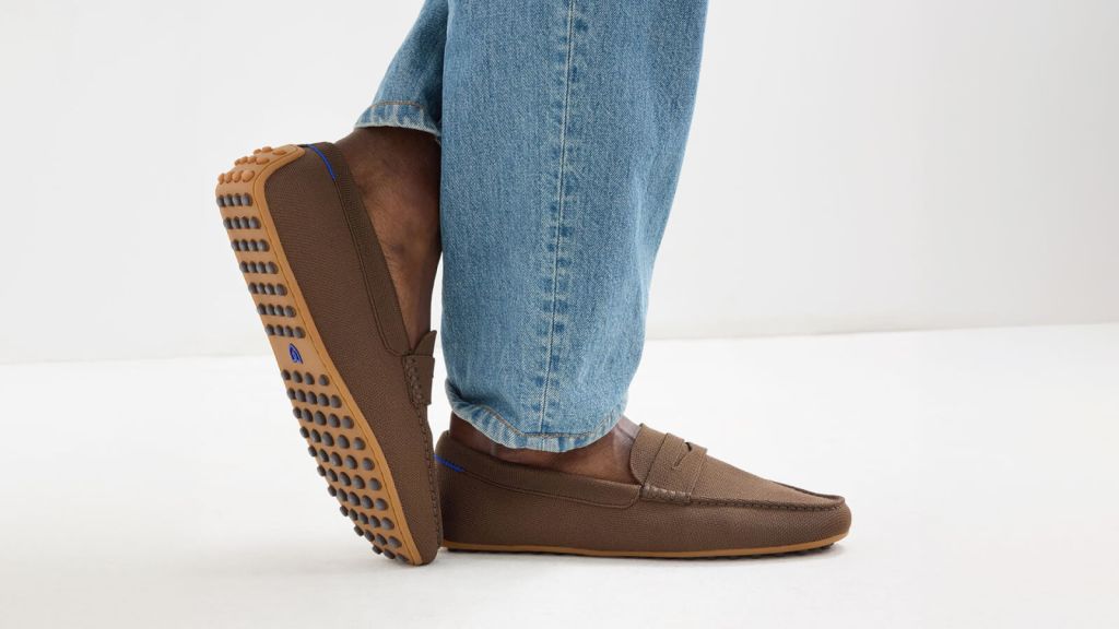 A person is wearing brown loafers with distinctive textured soles and blue jeans in Atlanta, Georgia.