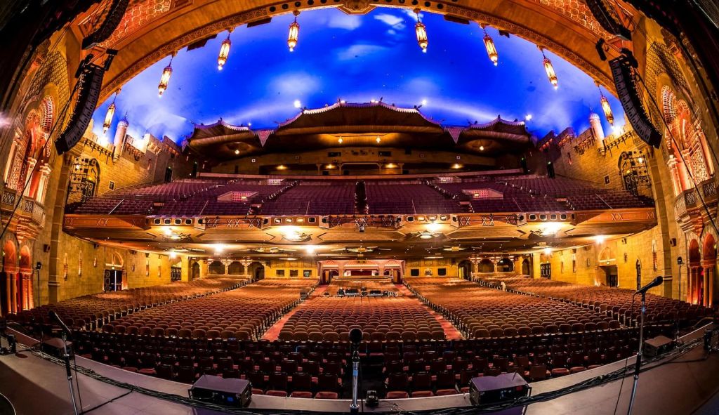 An ornate, empty theater with a blue-lit dome ceiling and rows of red seats in Atlanta, Georgia.