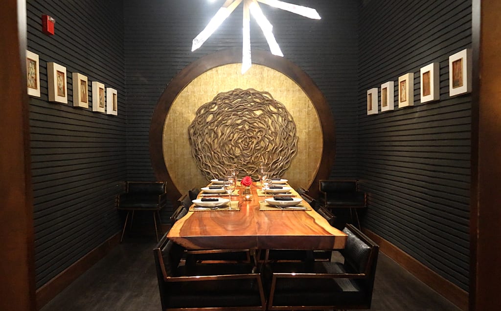 A modern dining room with a circular gold wall feature and a wooden table set for six in Atlanta, Georgia.