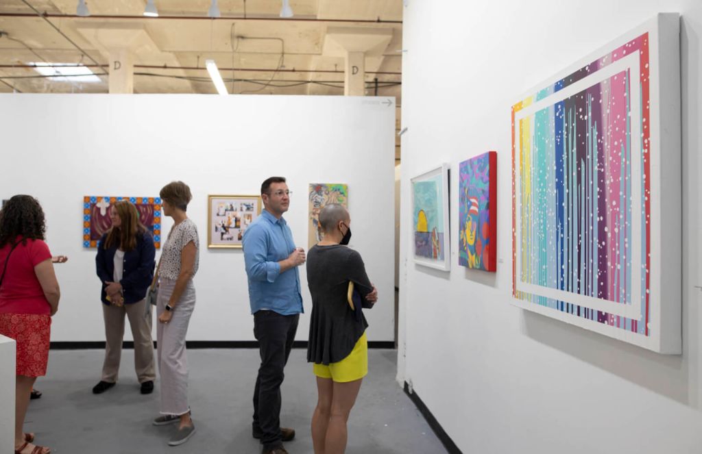 Visitors admire colorful abstract paintings in a modern art gallery with white walls in Atlanta, Georgia.