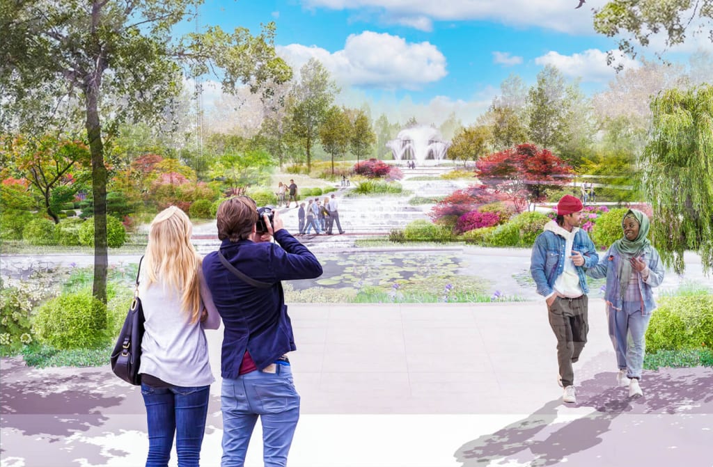 Three people stand on a bridge, one taking a photo of a vibrant garden with a fountain in Atlanta, Georgia.