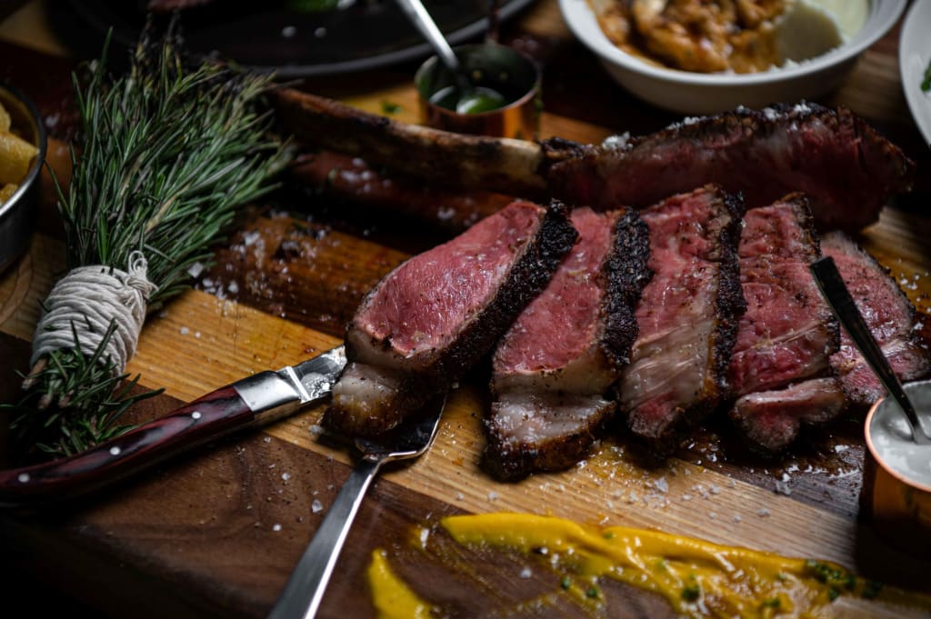 A beautifully presented steak with herbs and sauces on a wooden board in Atlanta, Georgia.