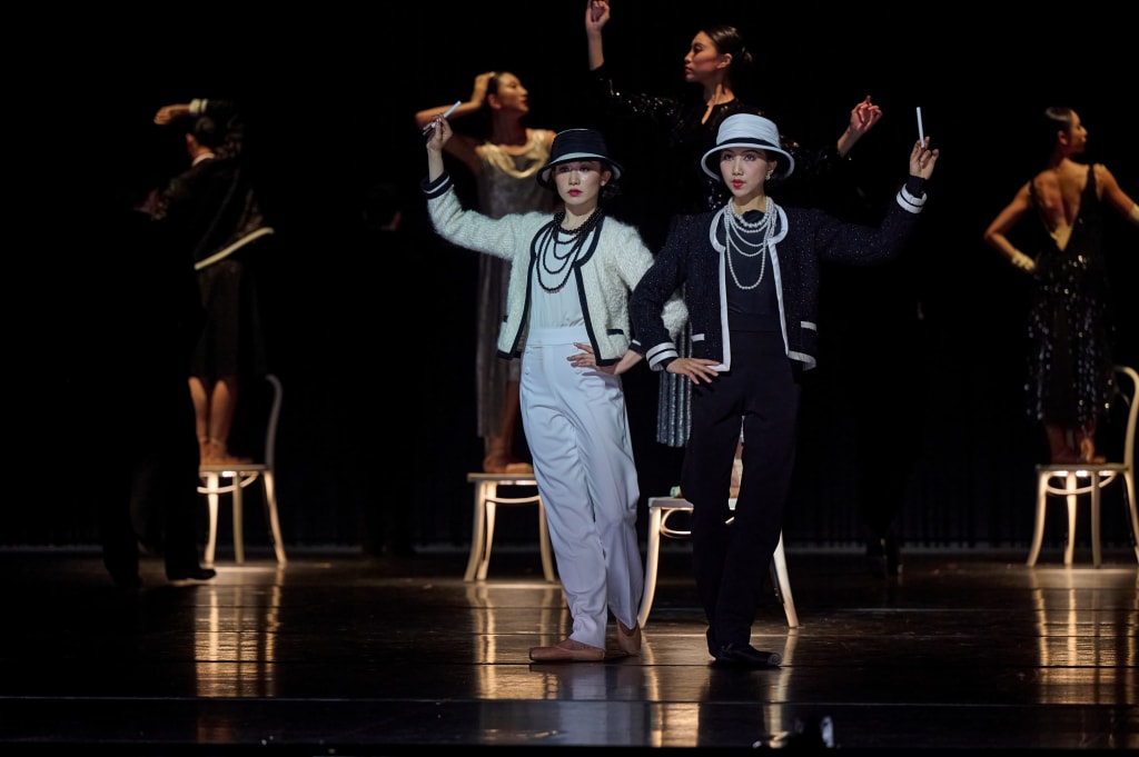 A group of dancers in 1920s-inspired costumes perform on stage, striking dynamic poses in Atlanta, Georgia.