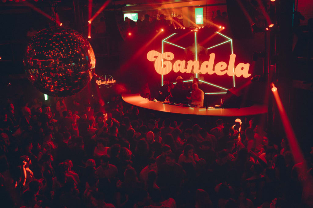 A crowded nightclub with a large disco ball and neon 'Candela' sign in Atlanta, Georgia.