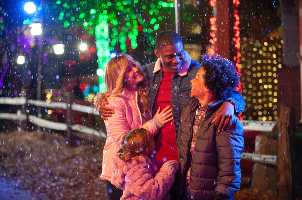 A family of four enjoys a snowy night together, surrounded by festive lights and decorations in Atlanta, Georgia.