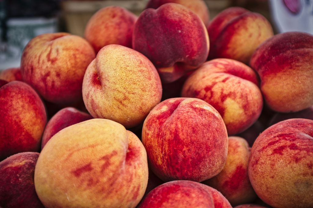 A pile of ripe, red peaches with yellow undertones and fuzzy skin in Atlanta, Georgia.