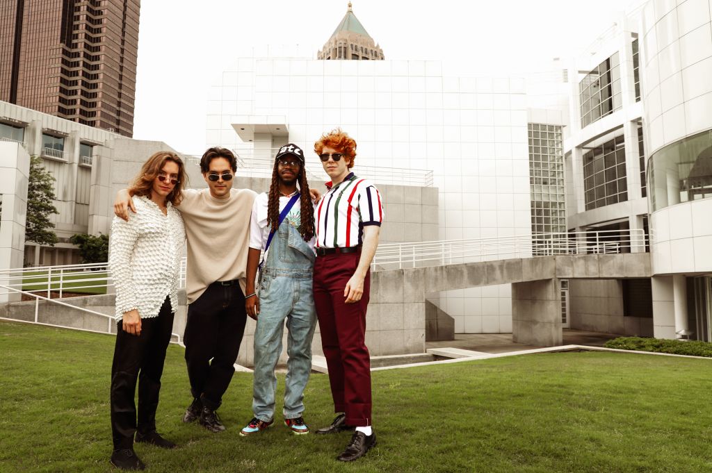 Four stylish individuals pose together on a grassy area in front of a modern architectural building complex in Atlanta, Georgia.