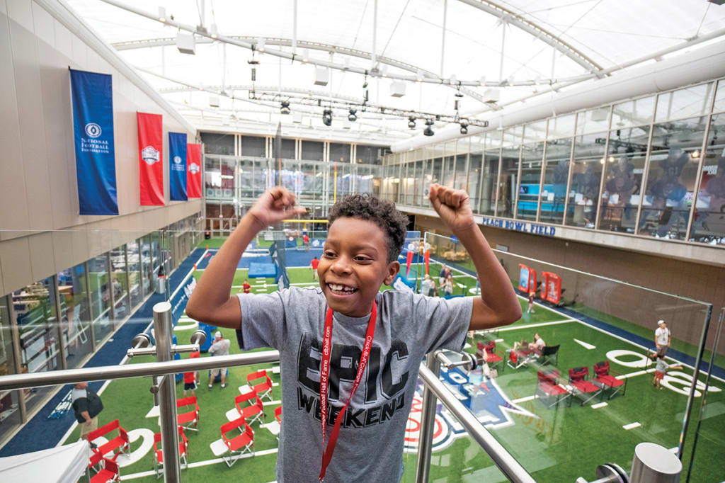 A young boy celebrates with arms raised in a large indoor sports facility in Atlanta, Georgia.