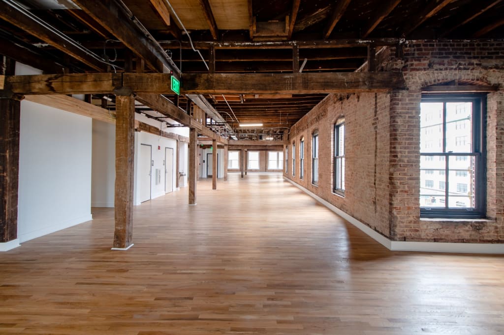 Spacious industrial loft with exposed brick walls, wooden beams, and polished floors in Atlanta, Georgia.