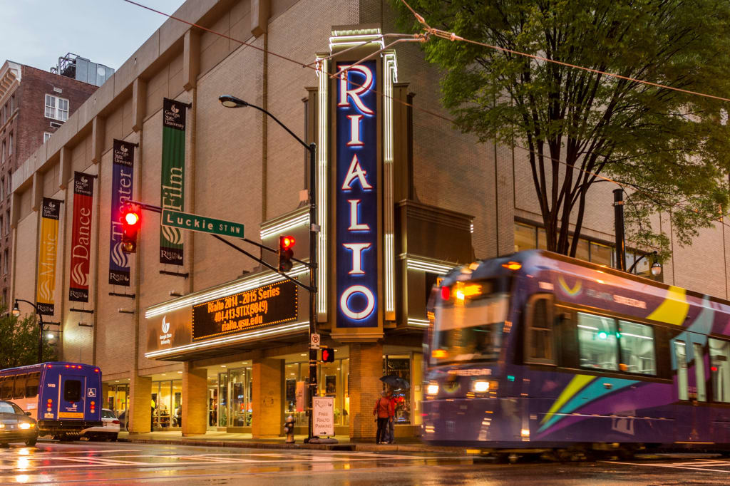 A purple streetcar passes by the Rialto Theatre on a rainy evening in Atlanta, Georgia.