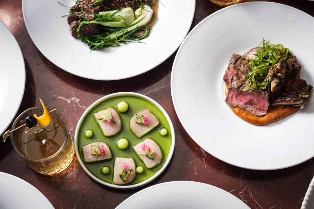 Ultimate Guide to Hotel Dining ATL Style 18 A variety of gourmet dishes, including steak, fish, and vegetables, are artfully presented on white plates in Atlanta, Georgia.