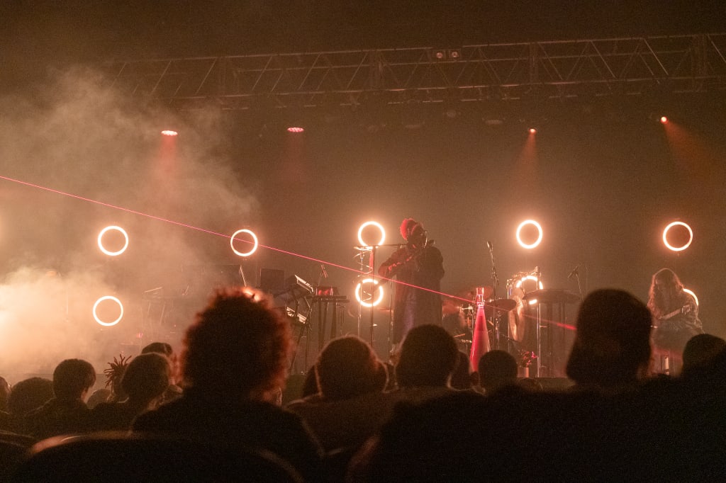 Trendy in Midtown 3 A musician performs on stage with glowing rings and smoke effects, while an audience watches in Atlanta, Georgia.