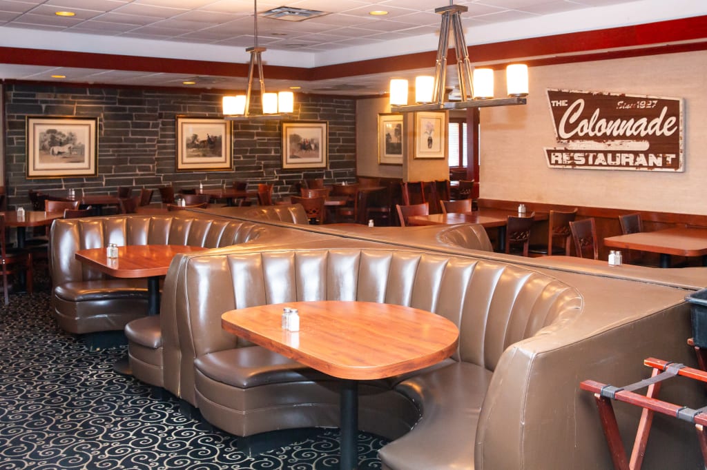 A cozy restaurant interior with curved leather booths, wooden tables, and framed artwork in Atlanta, Georgia.