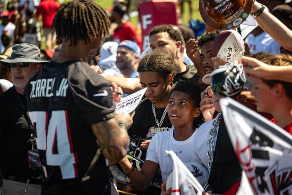 A group of young fans eagerly await autographs from Atlanta Falcons players at a training camp event in Atlanta, Georgia.
