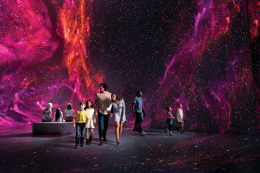 Boy, girl, men and woman walking and pointing in the middle of a space-like room.