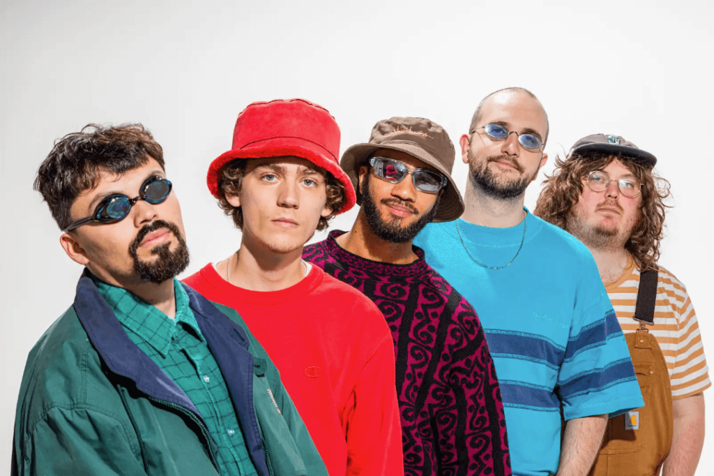 A group of five men pose together, each sporting unique styles of hats and sunglasses in Atlanta, Georgia.