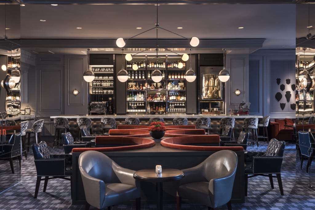 A modern, upscale bar with a curved red sofa, leather chairs, and a well-stocked liquor display in Atlanta, Georgia.