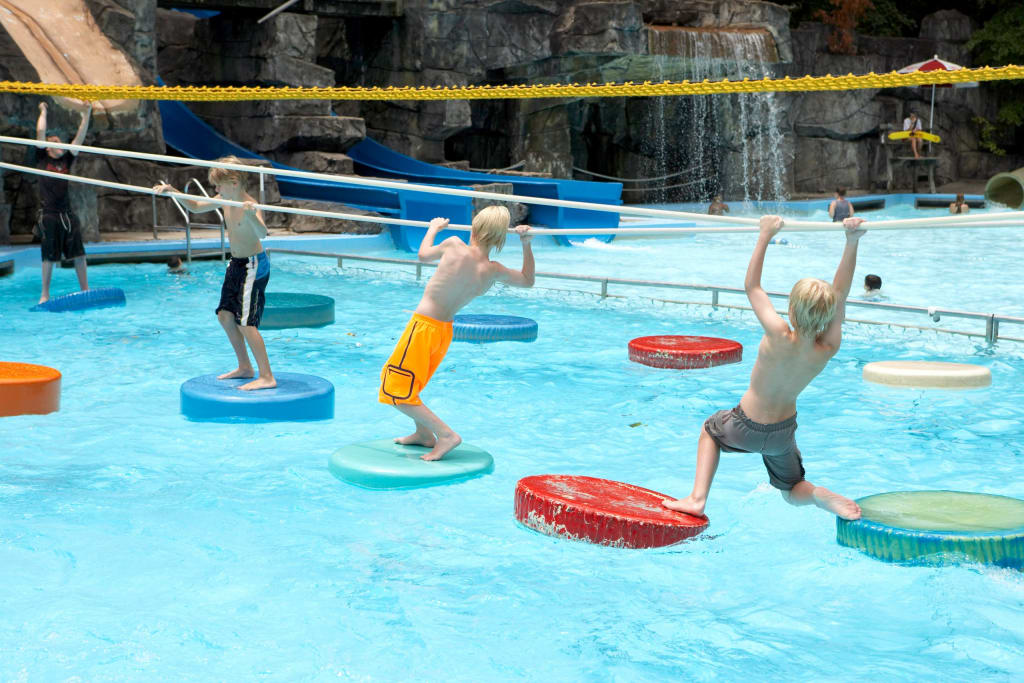 Kids walking across Six Flags White Water floating pads.