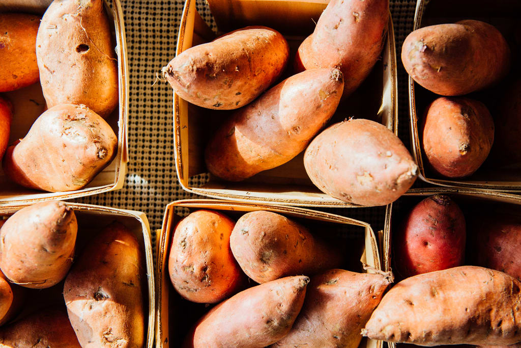 A collection of sweet potatoes in wooden crates, showcasing their rough, reddish-brown skin in Atlanta, Georgia.
