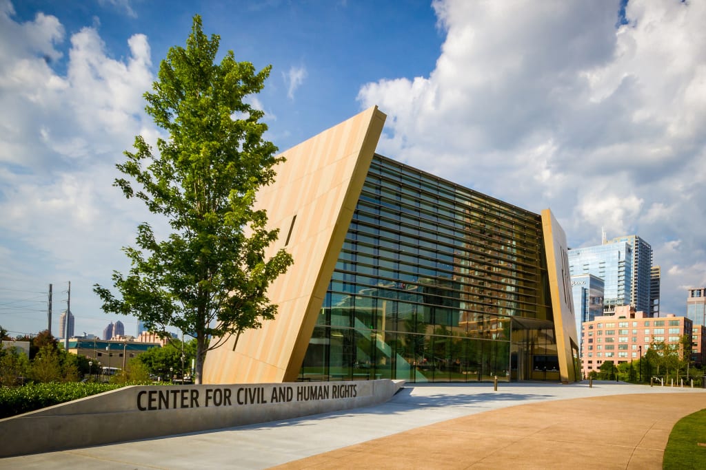 A modern building with a slanted glass facade and a sign reading 'Center for Civil and Human Rights' in Atlanta, Georgia.