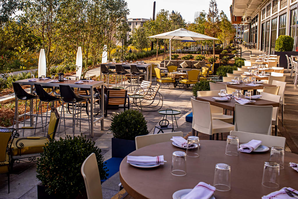 Outdoor restaurant patio with tables, chairs, umbrellas, and potted plants in Atlanta, Georgia.