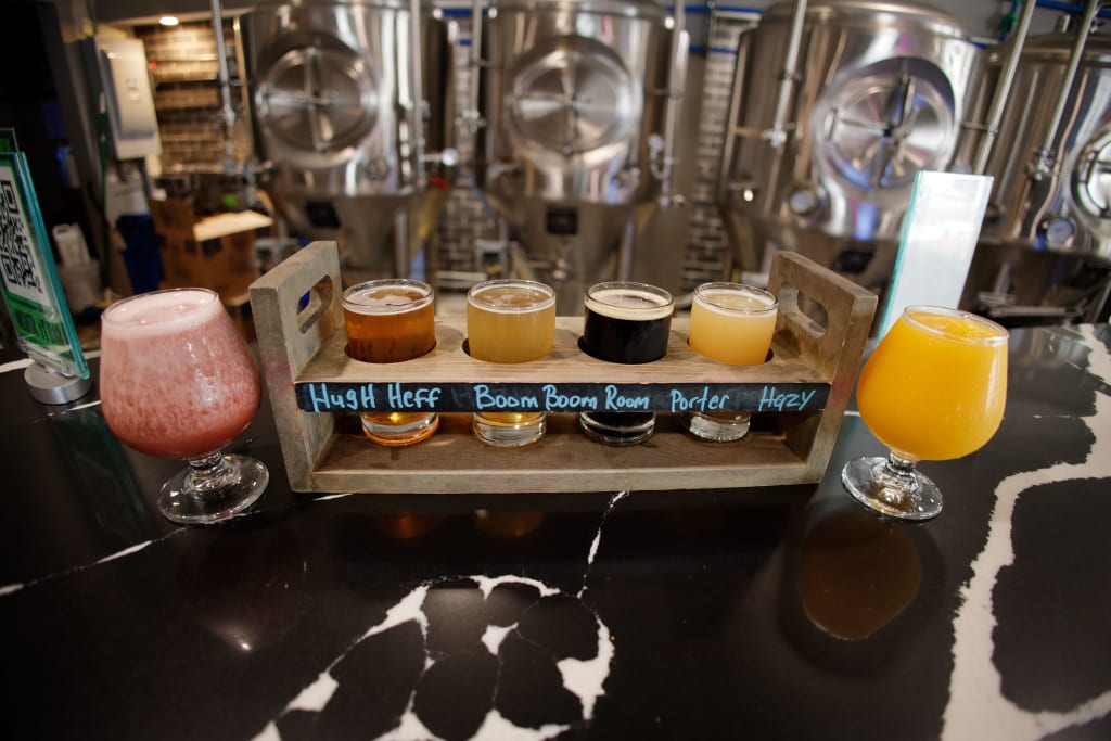A wooden beer flight tray holds five different craft beers, each labeled with its name in Atlanta, Georgia.